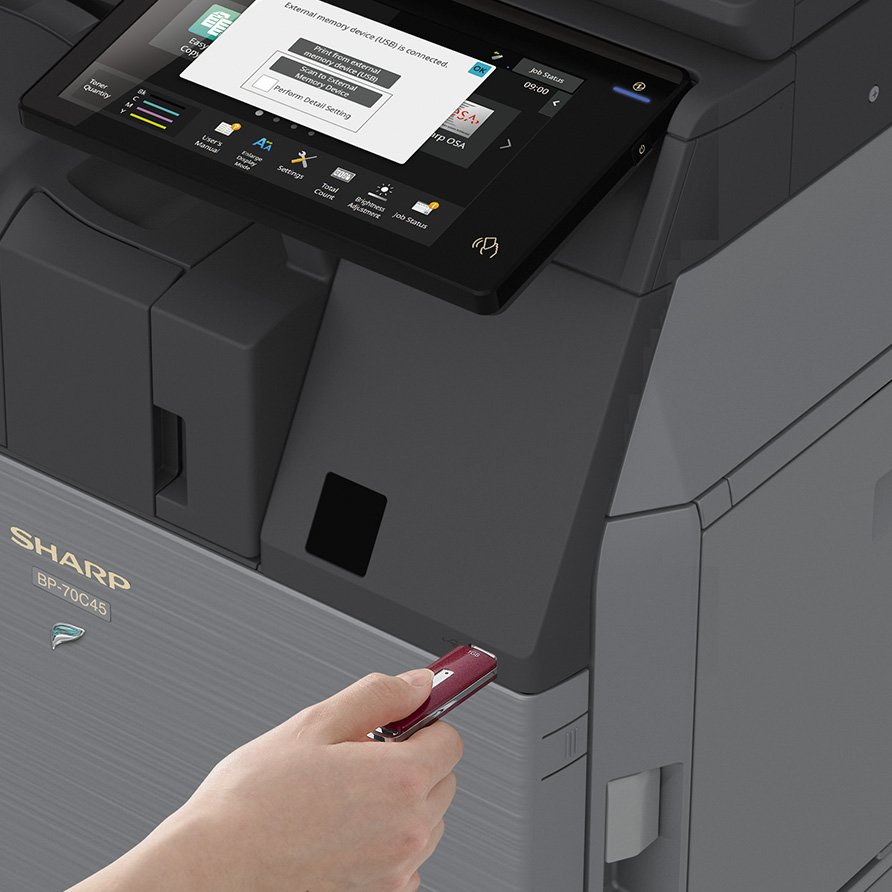 Person plugging in USB device to the front of the Sharp Copier